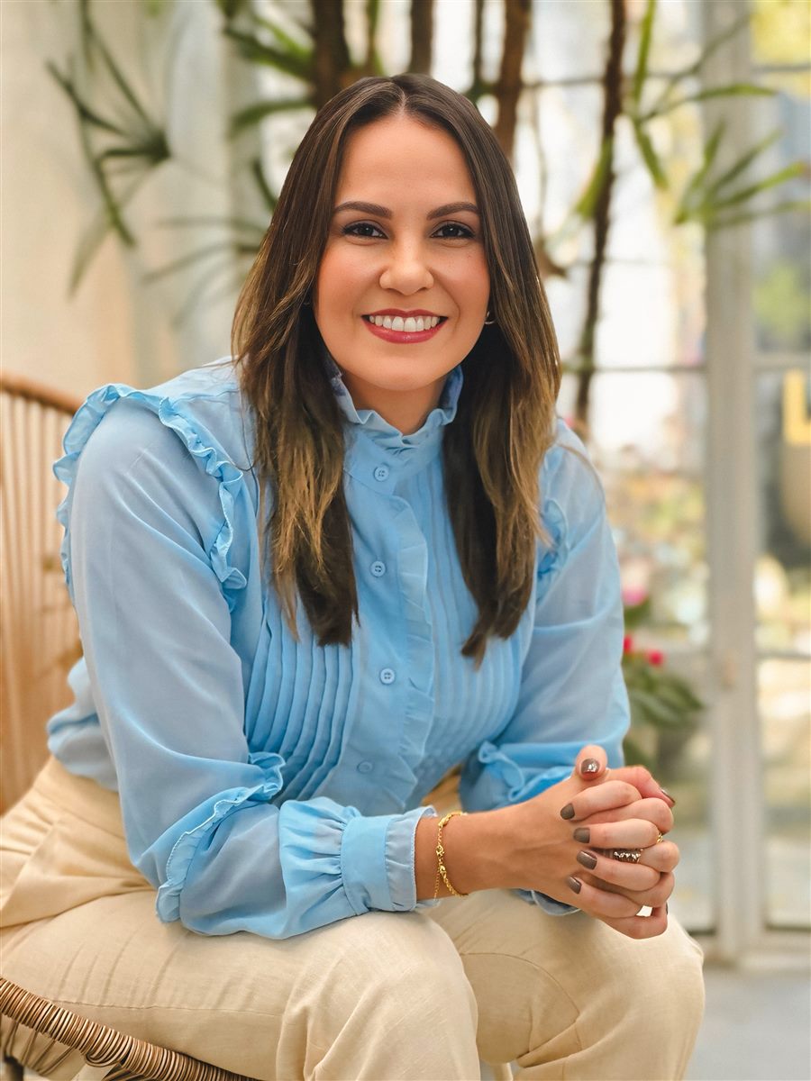 Dra. Luana Figuerêdo sentada, sorrindo, cercada de plantas
